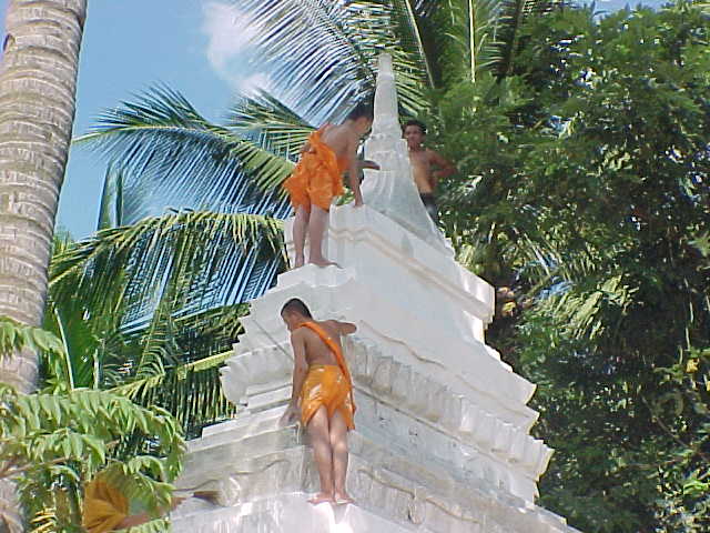 Monks whitwashing a stupa (Laos, The Travel Addicts)