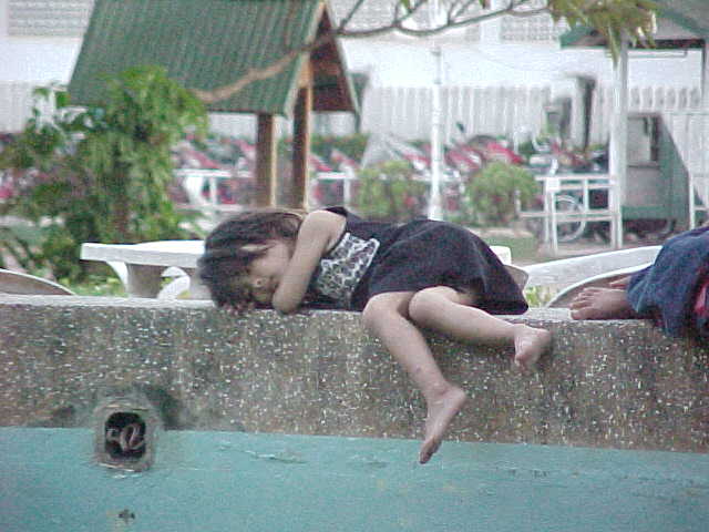 Laotian girl sleeping on fountain in centre of city (Laos, The Travel Addicts)