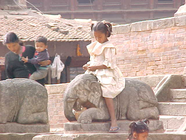 Little girl enjoying elephant statue (Nepal, The Travel Addicts)